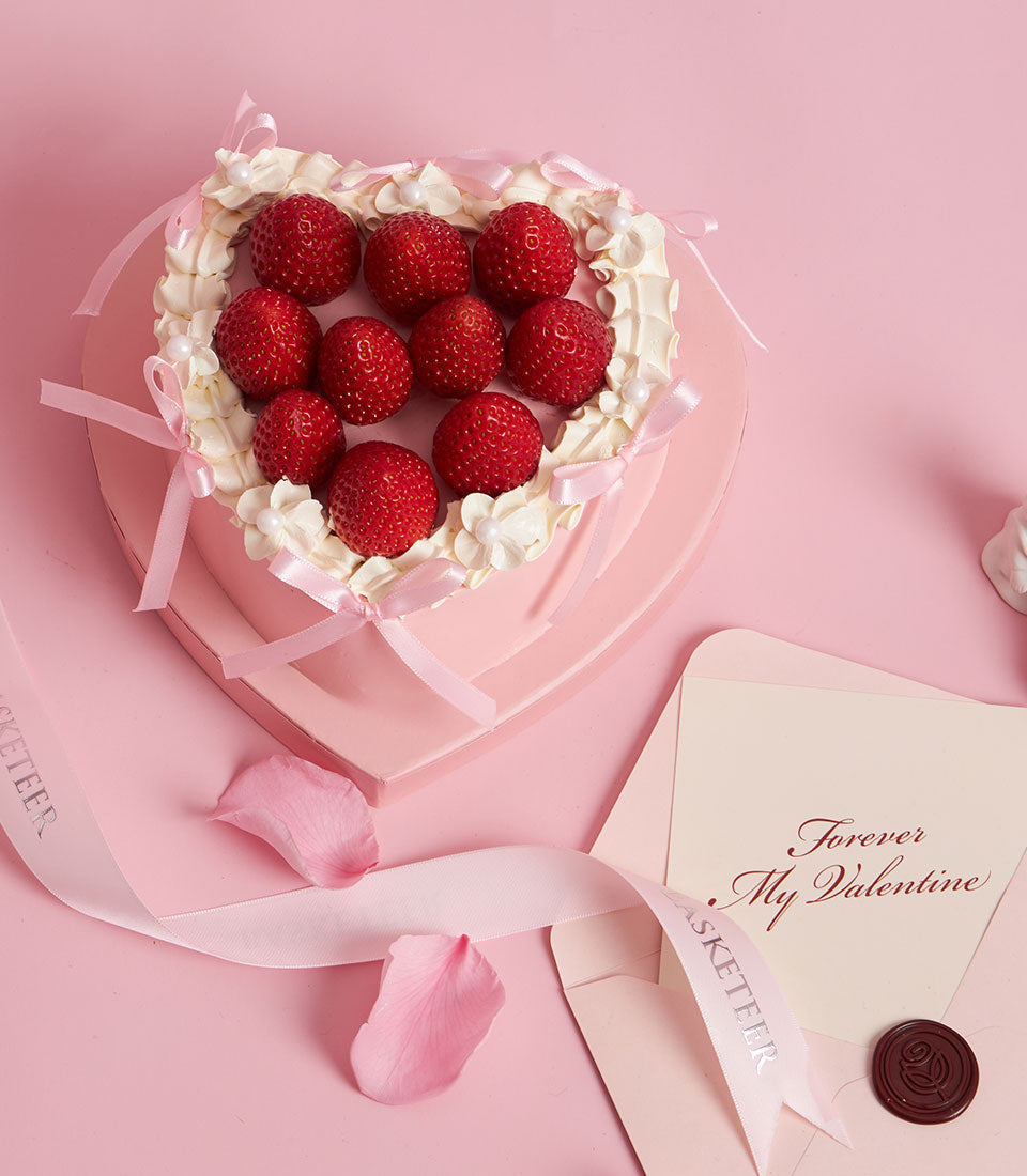 Heart-shaped custom cake Bangkok delivery from Charlotte Bakery. Fresh strawberries on pink cream artisan cake with delicate ribbon detail. British bakery Thailand.