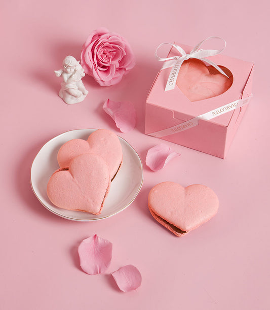 Charlotte Bakery heart-shaped cookies: delicate pink artisan pastries in a gift box, ideal for birthday cake delivery Bangkok. Features rose and cherub accents.