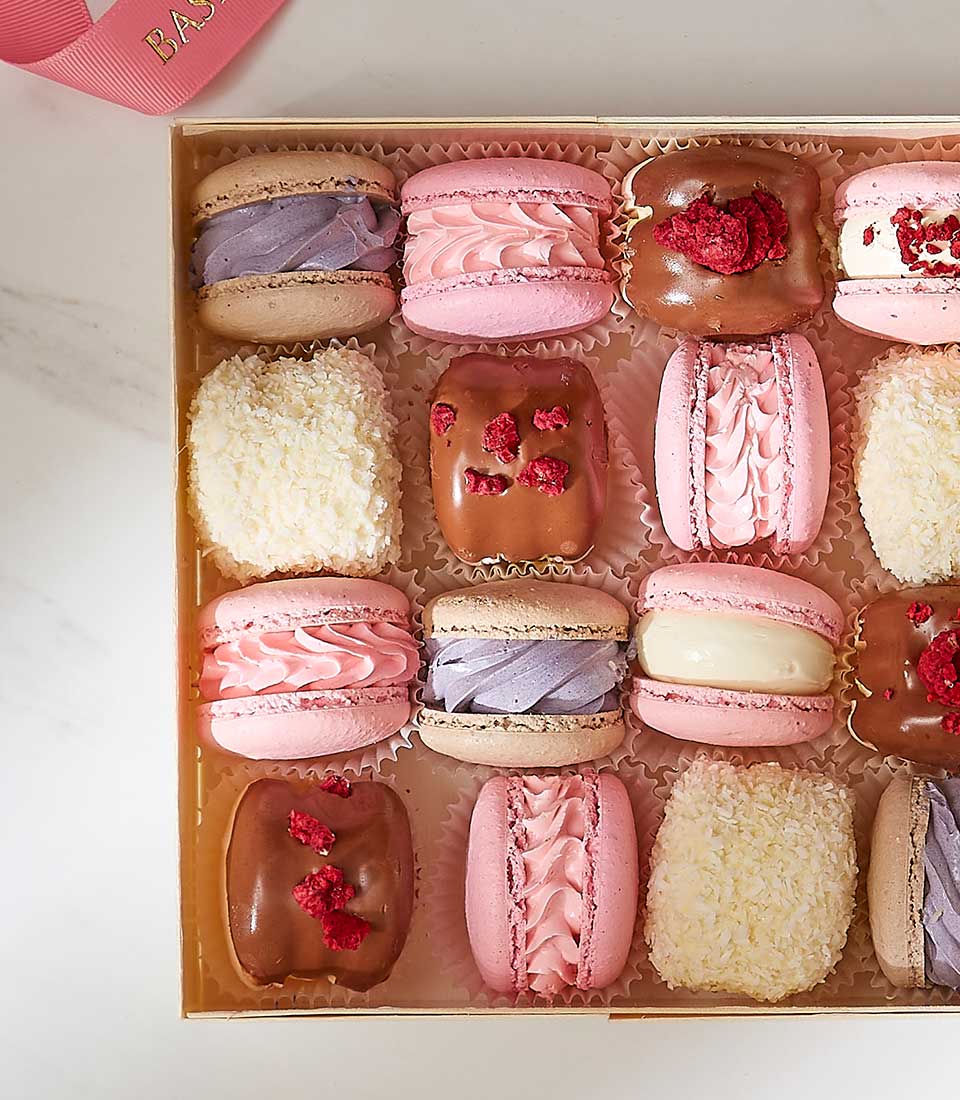 Assorted pastel macarons and chocolates in luxury gift box with pink ribbon