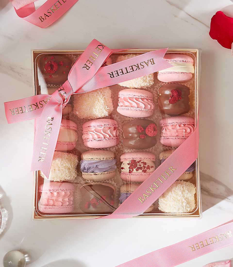 Assorted macarons and chocolate pastries in gift box with pink ribbon