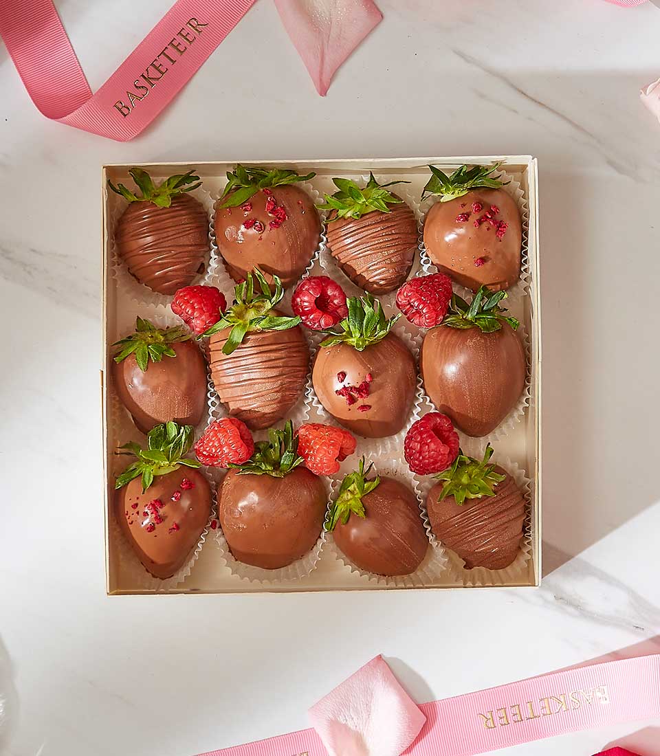 Luxury chocolate-covered strawberries gift box with milk chocolate drizzle and raspberry accents for Valentine's Day