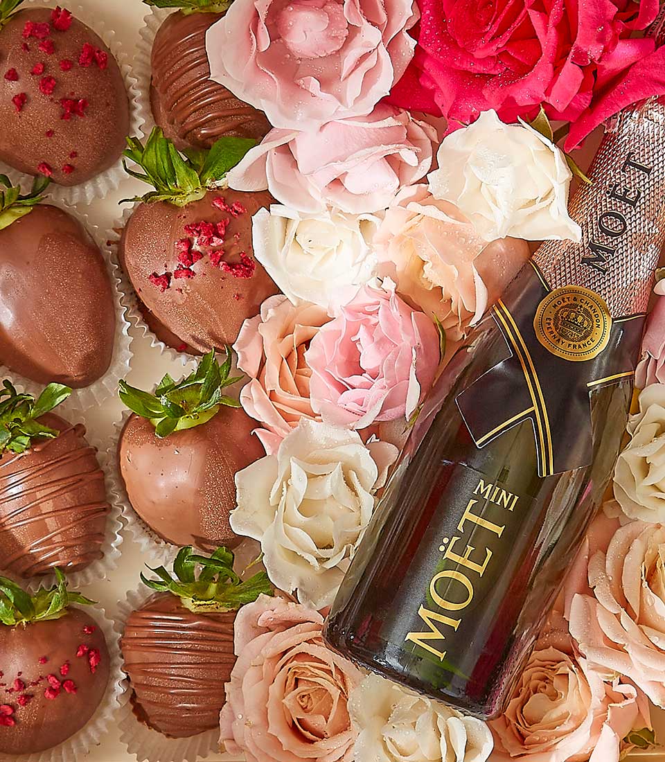 Luxurious Valentine gift with chocolate strawberries, pink and peach roses, and mini champagne bottle