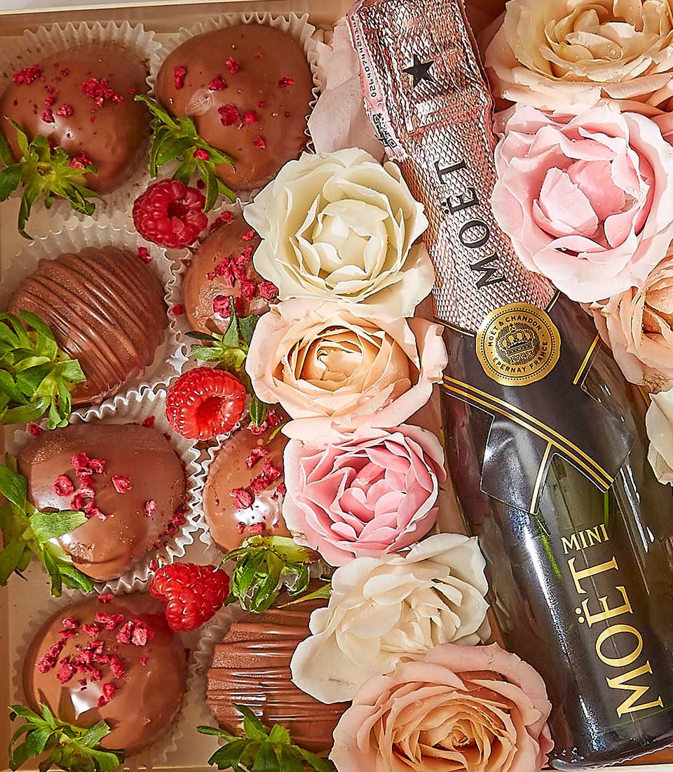 Champagne, chocolate-covered strawberries, and fresh roses in luxury Valentine's gift box