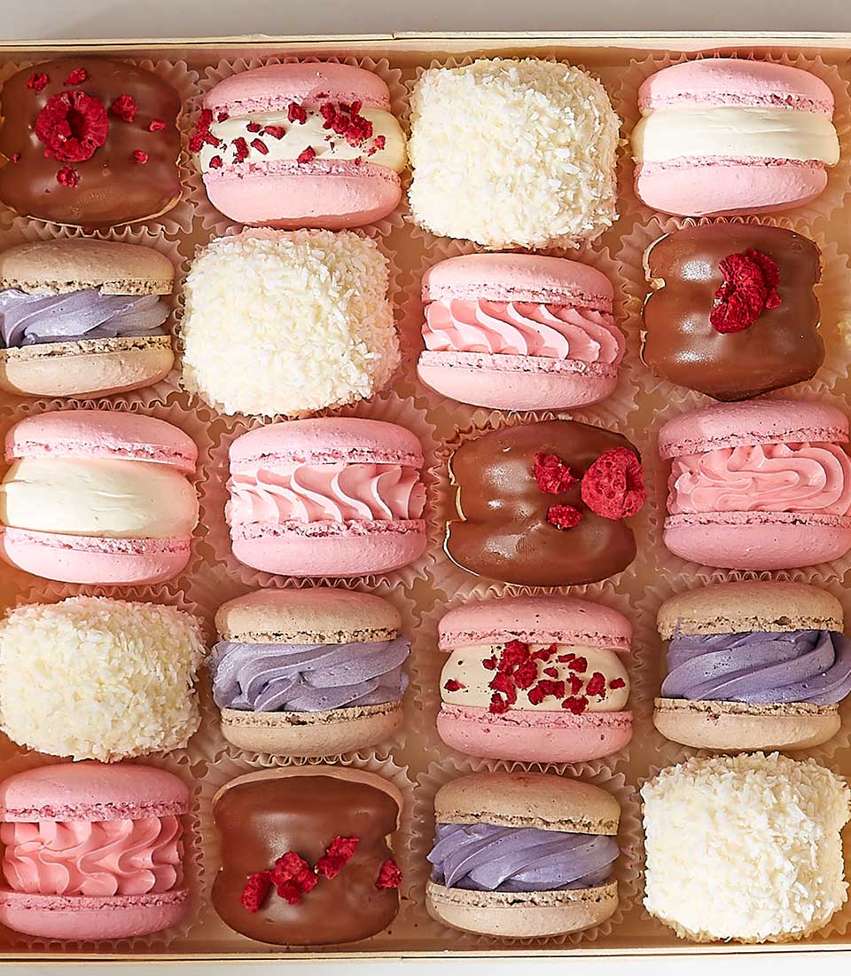 Assorted pastel macarons gift box with raspberry, chocolate, and coconut treats in fluted cups