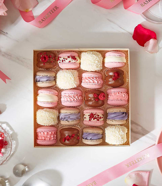 Assorted pastel macarons gift box with pink, purple, and white shells, gold-edged luxury packaging for celebrations