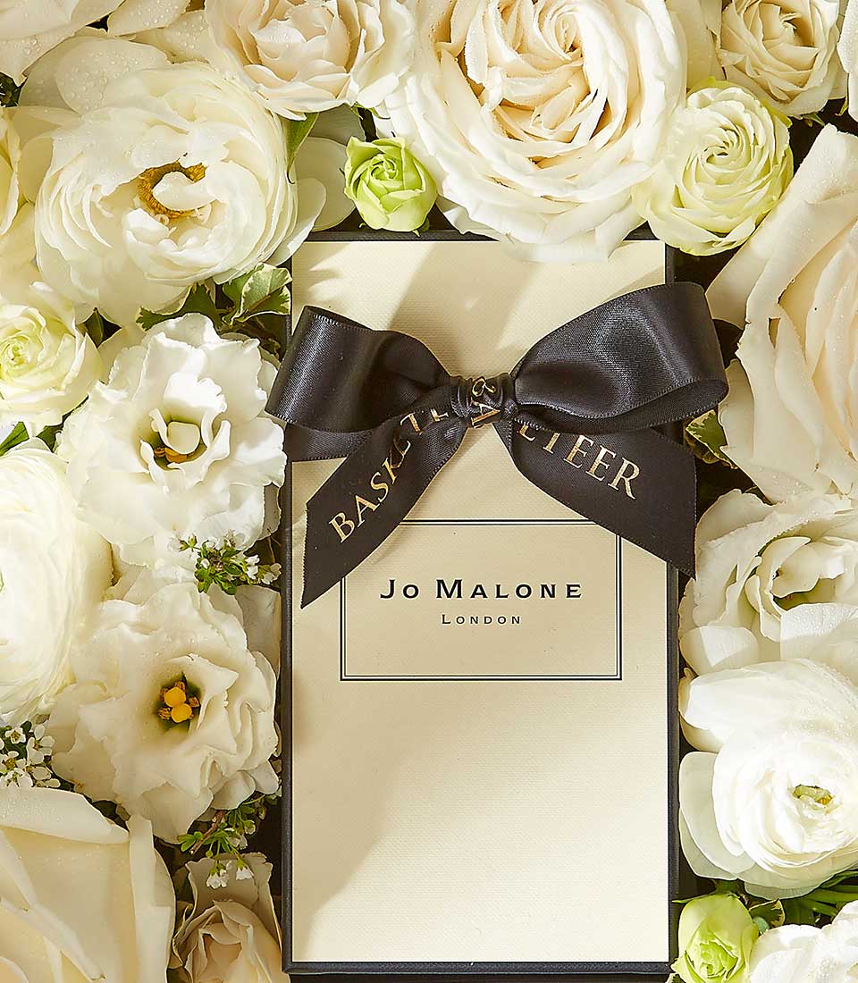 Jo Malone London English Pear Perfume gift set surrounded by white roses and ranunculus in cream gift box with black ribbon