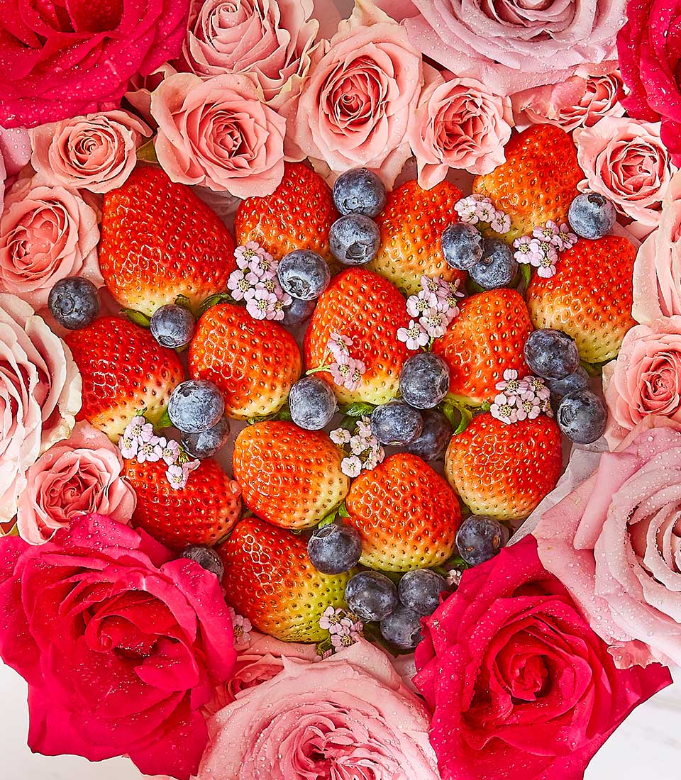 Heart-shaped fresh strawberry and blueberry arrangement with Ecuadorian roses in pink and peach, perfect for birthdays and