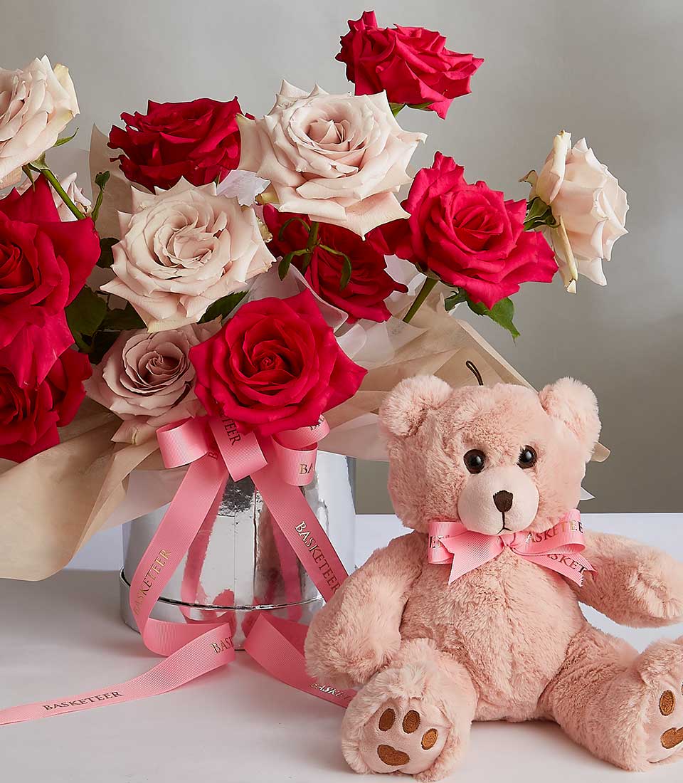 Red and blush pink rose bouquet with plush teddy bear in silver cylinder, tied with pink ribbon for birthdays or special