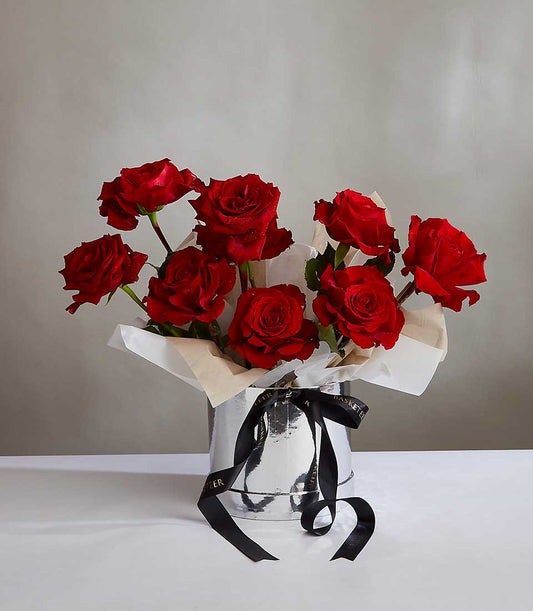 Vibrant red roses in silver cylinder with black and gold ribbon, fresh anniversary gift for her