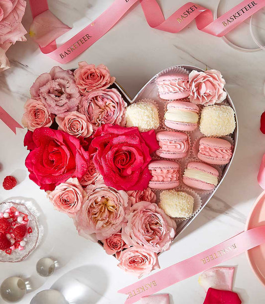 Heart-shaped luxury gift box with fresh pink roses, pink macarons, and white coconut confections for birthdays and