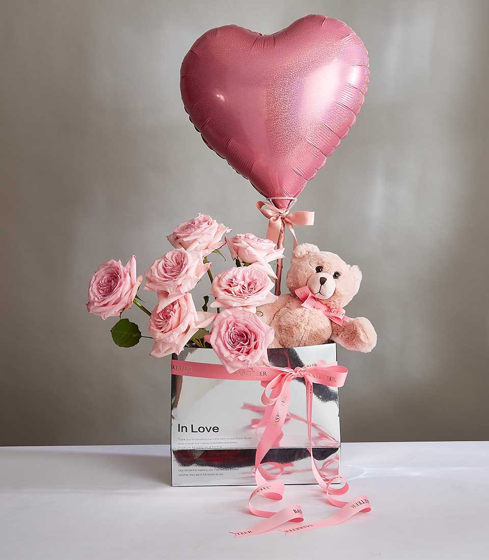Metallic pink heart balloon with fresh rose bouquet, teddy bear, and luxury gift box for Valentine's Day