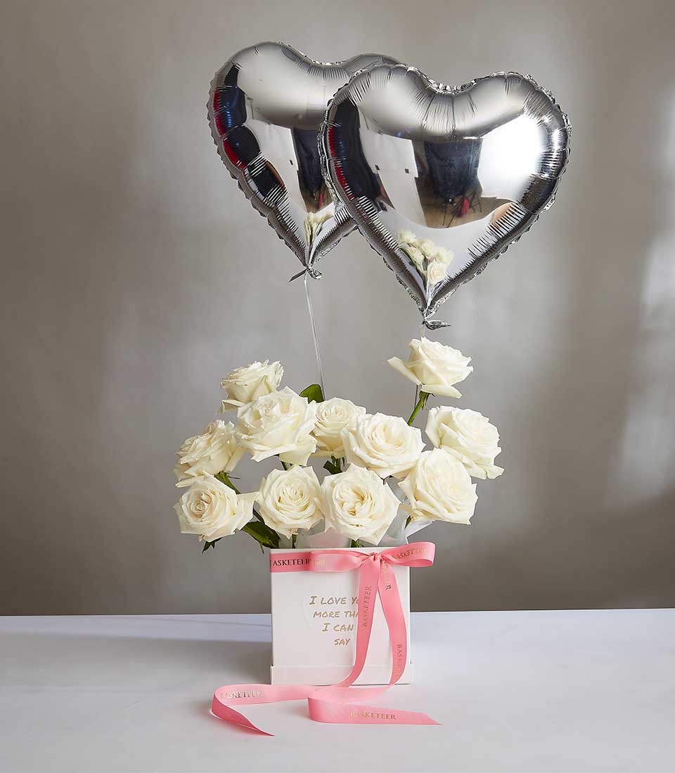 White rose bouquet with silver heart balloons and pink ribbon, Valentine's Day gift box with "I love you more than I can