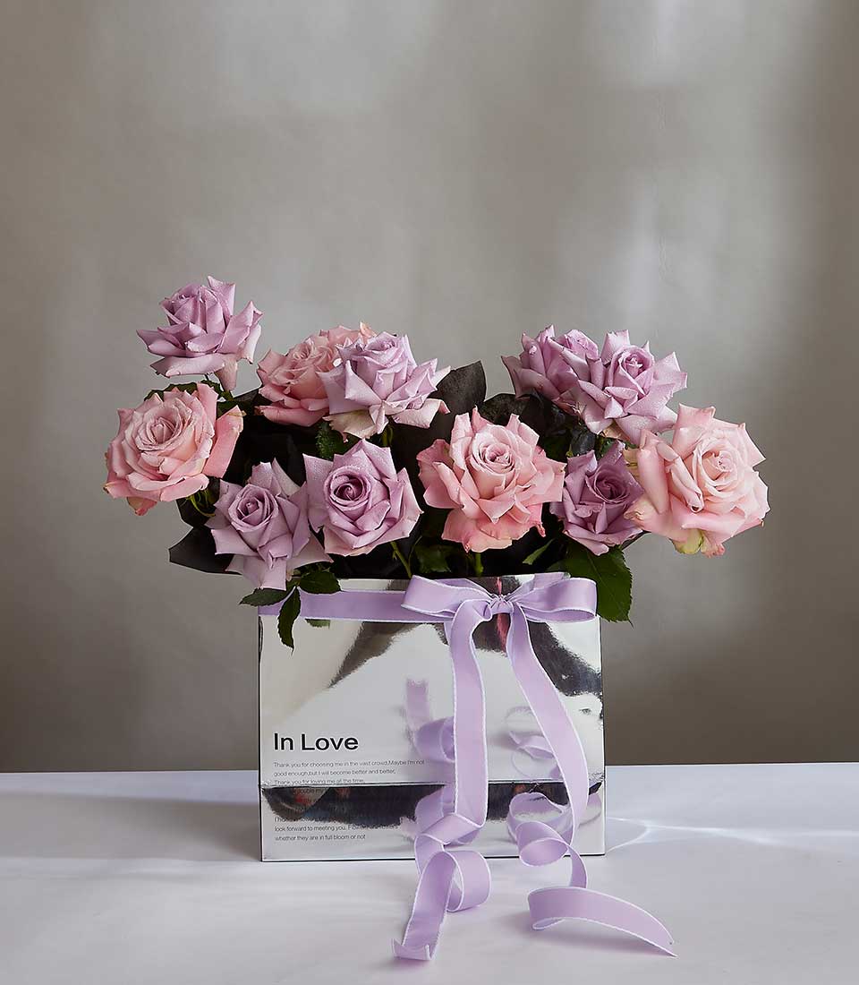Soft pink and purple roses with water droplets in silver gift box tied with lavender ribbon, anniversary flowers for her