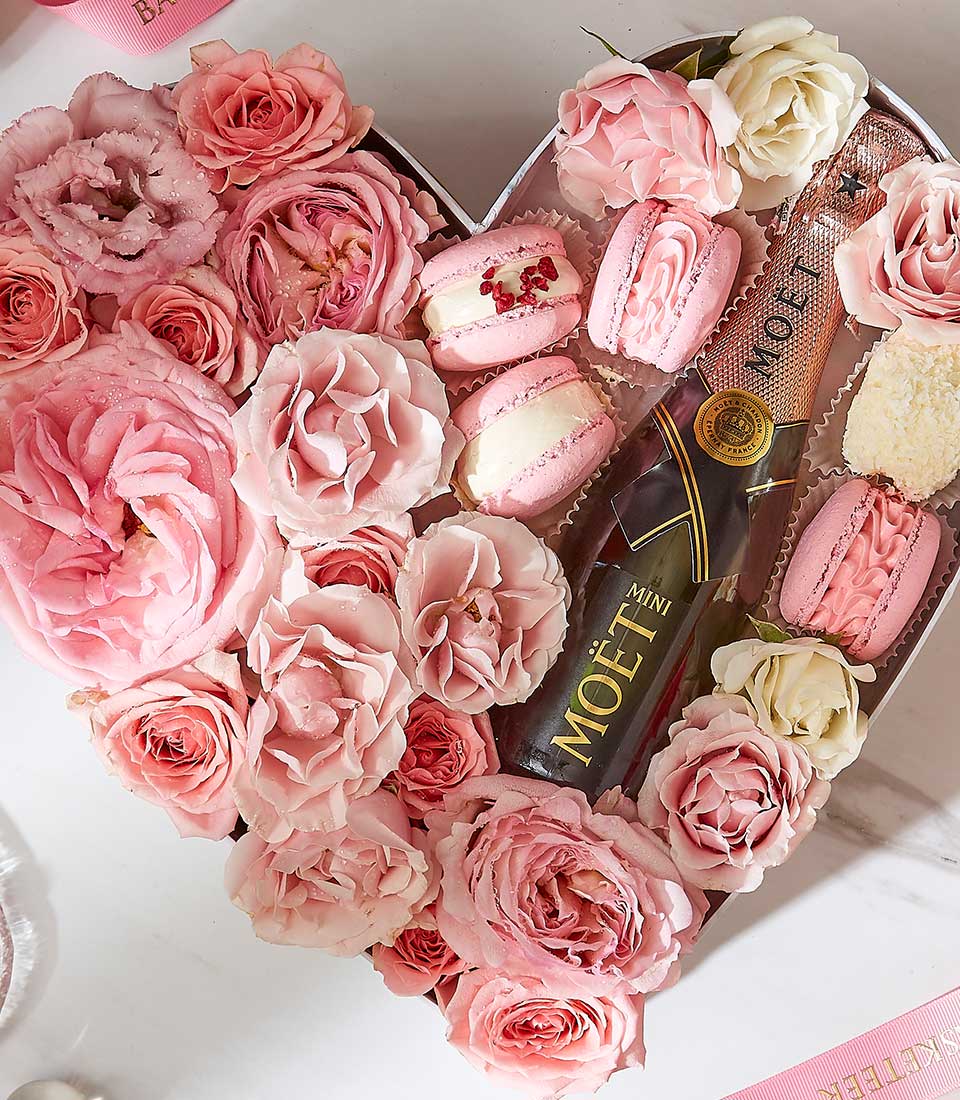 Luxury heart-shaped gift box with pink roses, champagne, and rose-flavored macarons for Valentine's Day