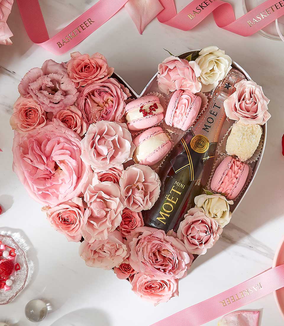Heart-shaped Valentine gift box with pink roses, Moët champagne, macarons, and raspberries