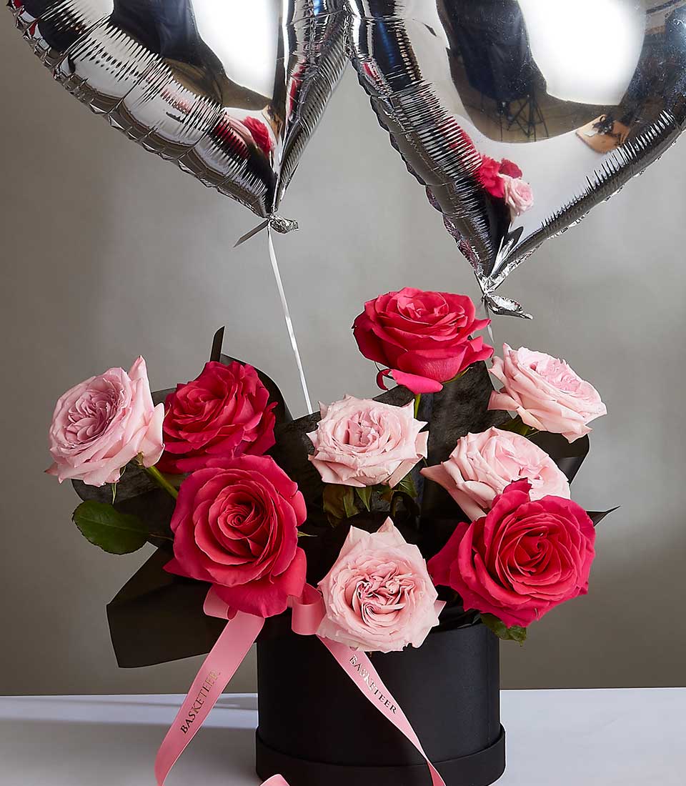 Pink and red roses in black hatbox with silver heart balloons, Valentine's Day luxury gift arrangement