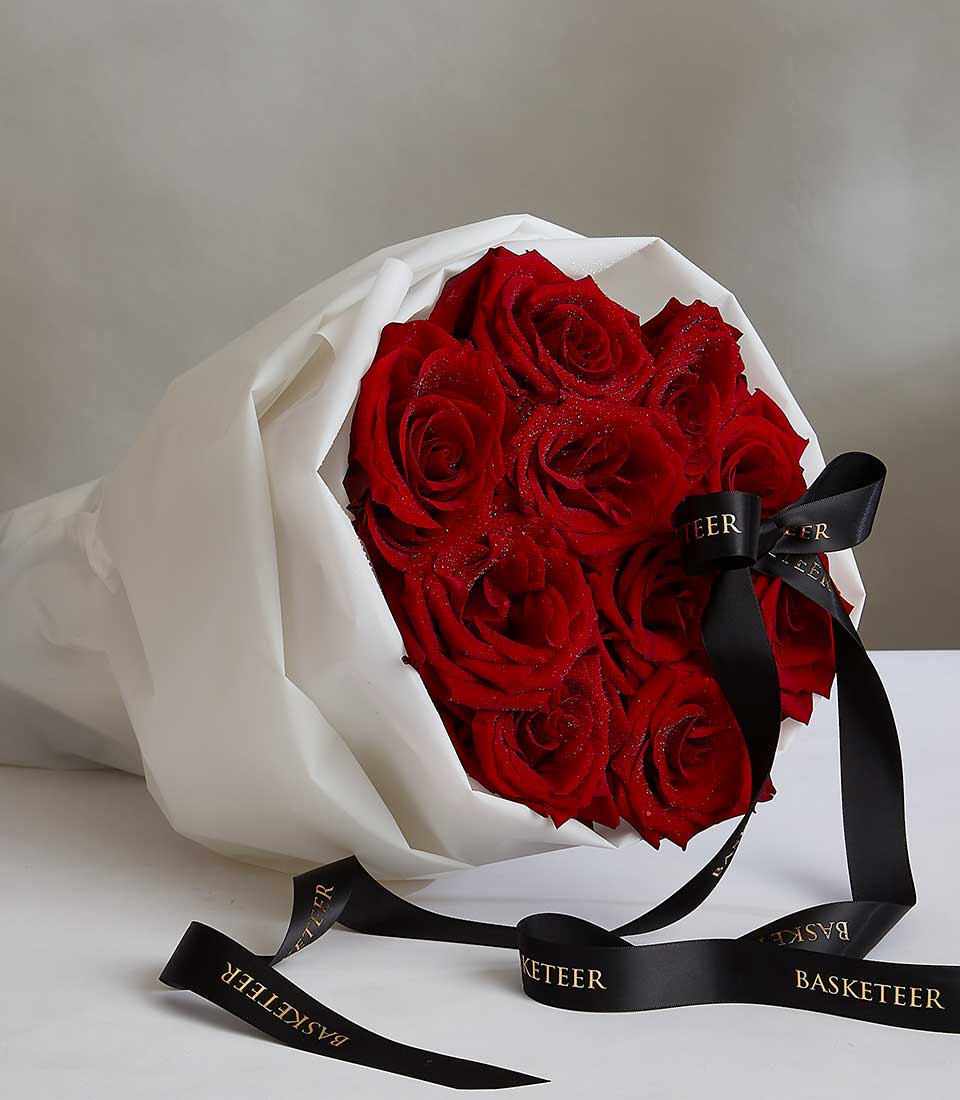 Romantic red rose bouquet with white paper wrapping and black satin ribbon