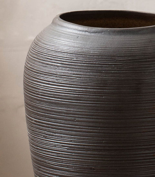 Handcrafted dark charcoal ceramic vase with horizontal ridged texture and rounded bulbous shape