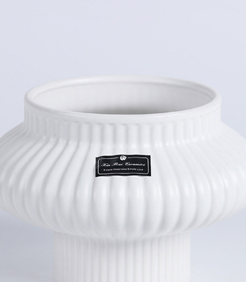 White fluted ceramic vase with ribbed vertical design and narrow cylindrical base