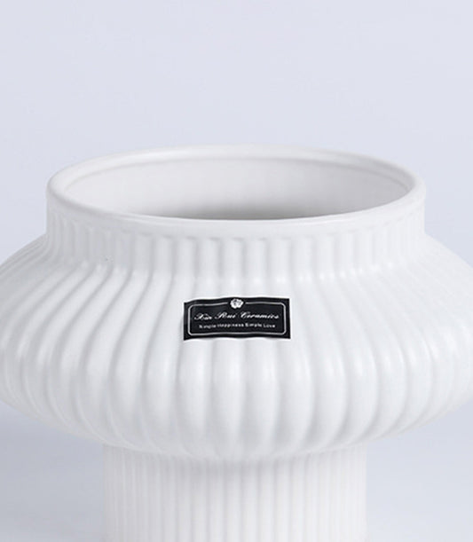 White fluted ceramic vase with ribbed vertical design and narrow cylindrical base