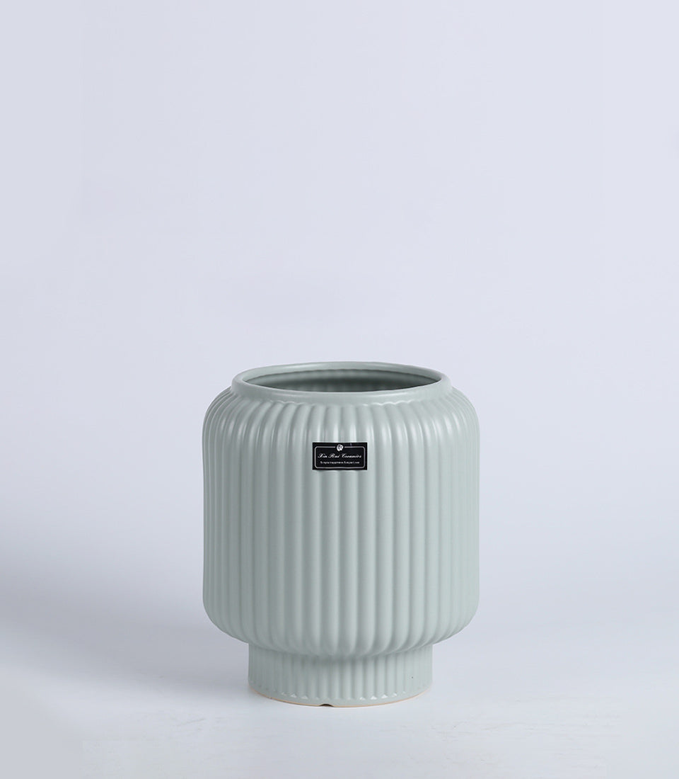 Sage green ceramic vase with ribbed texture and tapered cylindrical form