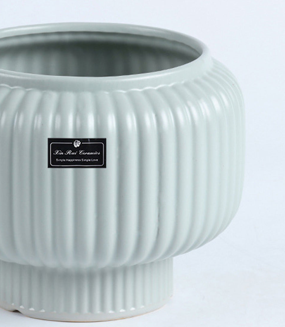 Light sage green ceramic vase with ribbed design and footed base, perfect for premium gifting