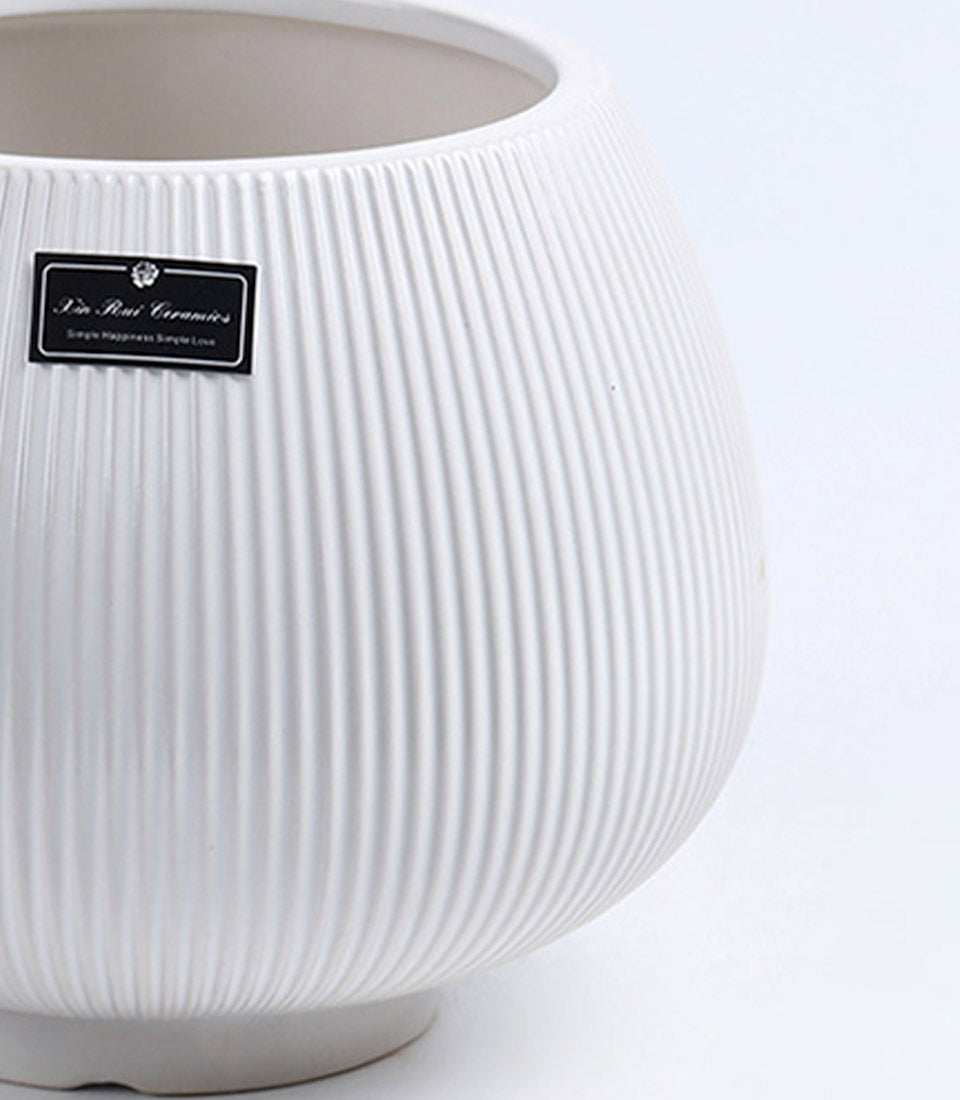 White ribbed ceramic vase with rounded bulbous form and artisan handcrafted texture