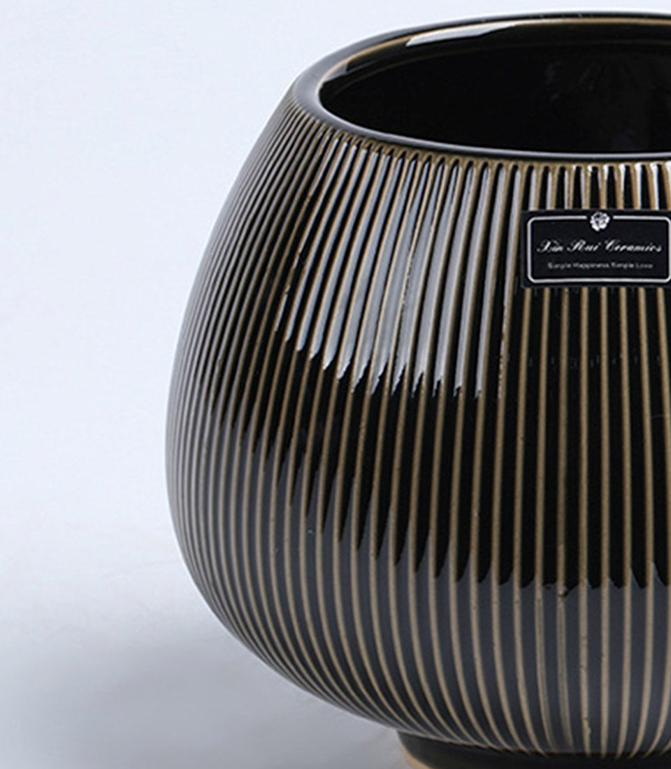 Black ceramic vase with metallic gold ribbed stripes and tapered rounded body for elegant home styling