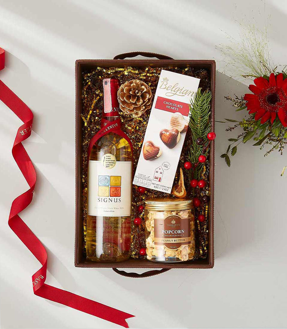Festive wine gift box with white wine, Belgian chocolates, peanut butter popcorn, and holiday decorations