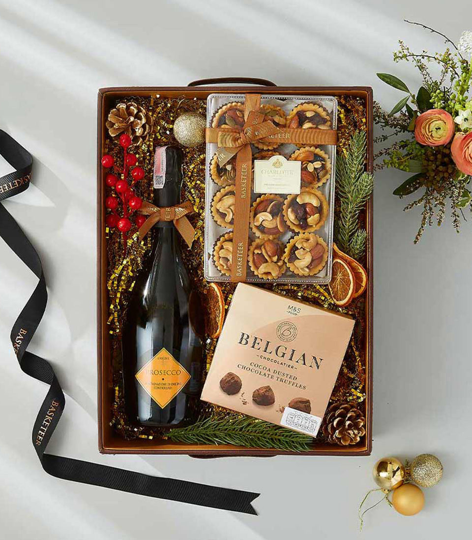 Premium red wine gift hamper with Belgian chocolates, artisan tarts, and festive gold shredded paper styling
