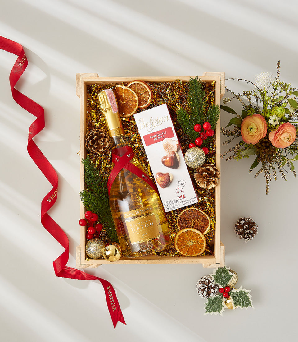 Luxury champagne gift box with Belgian chocolate hearts, festive gold accents, and holiday florals