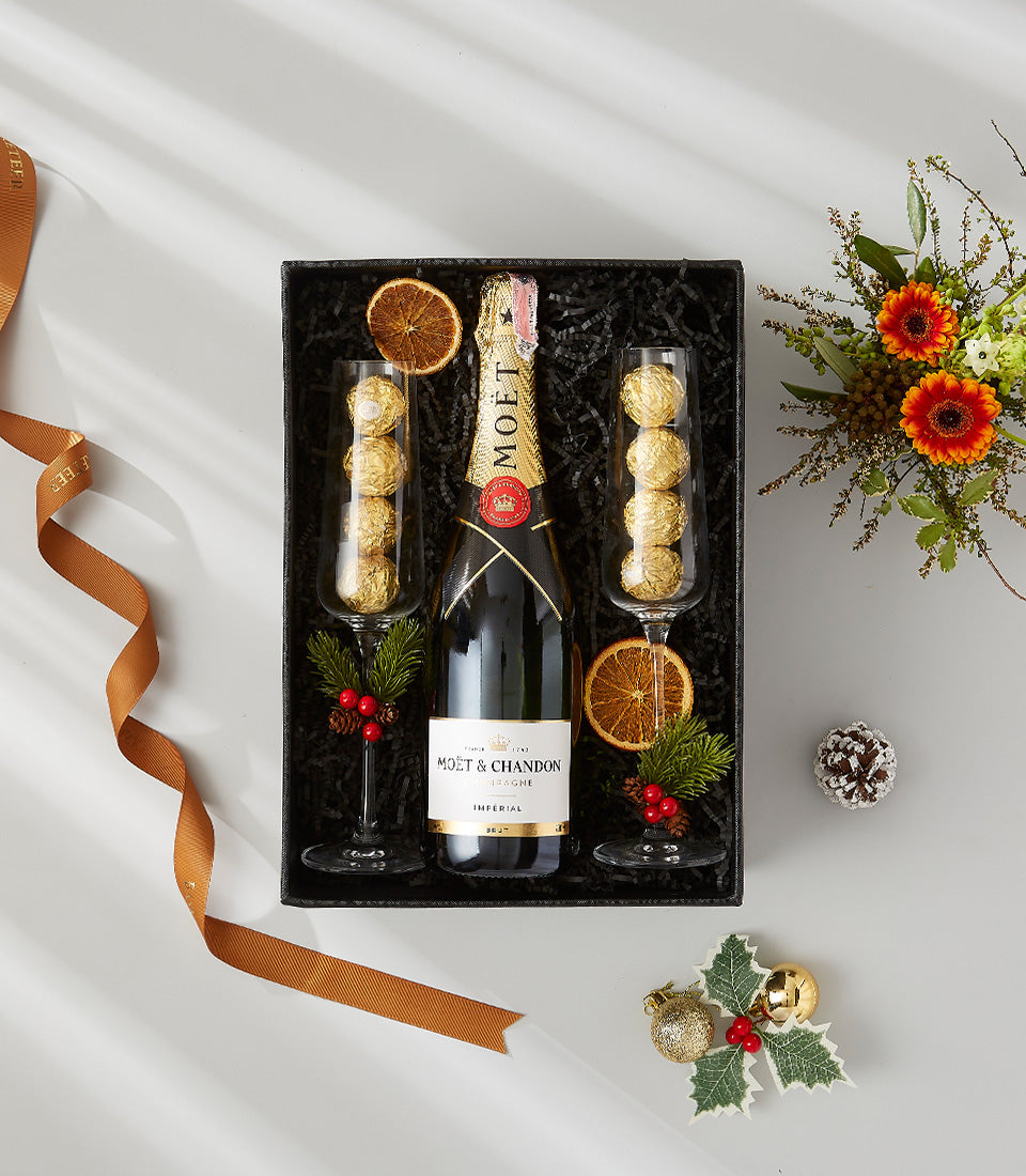 Luxury Moet champagne gift hamper with flutes, chocolates, and festive holiday decorations in elegant black box