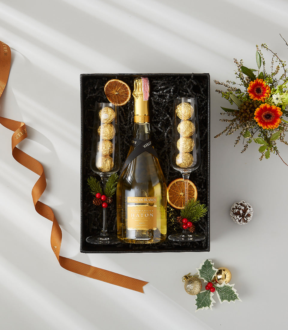Premium Champagne gift hamper with Blanc de Blancs, champagne flutes, gold chocolates, and festive florals