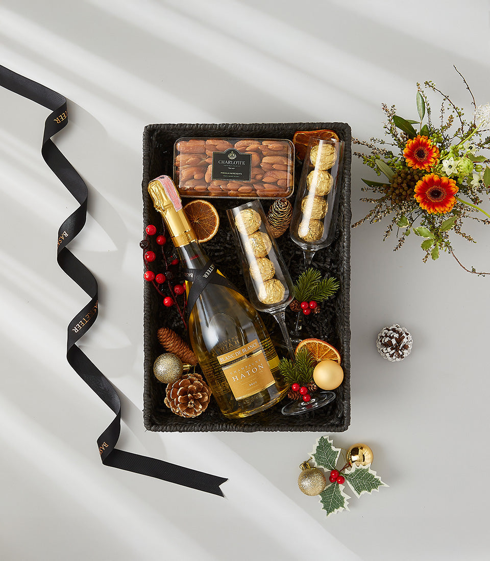 Premium champagne gift hamper with chocolates, almonds, and festive decorations in woven basket
