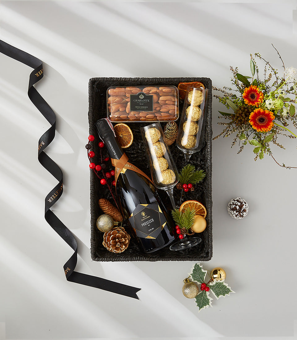 Prosecco gift basket with champagne flutes, chocolates, almonds, red berries and holiday decorations