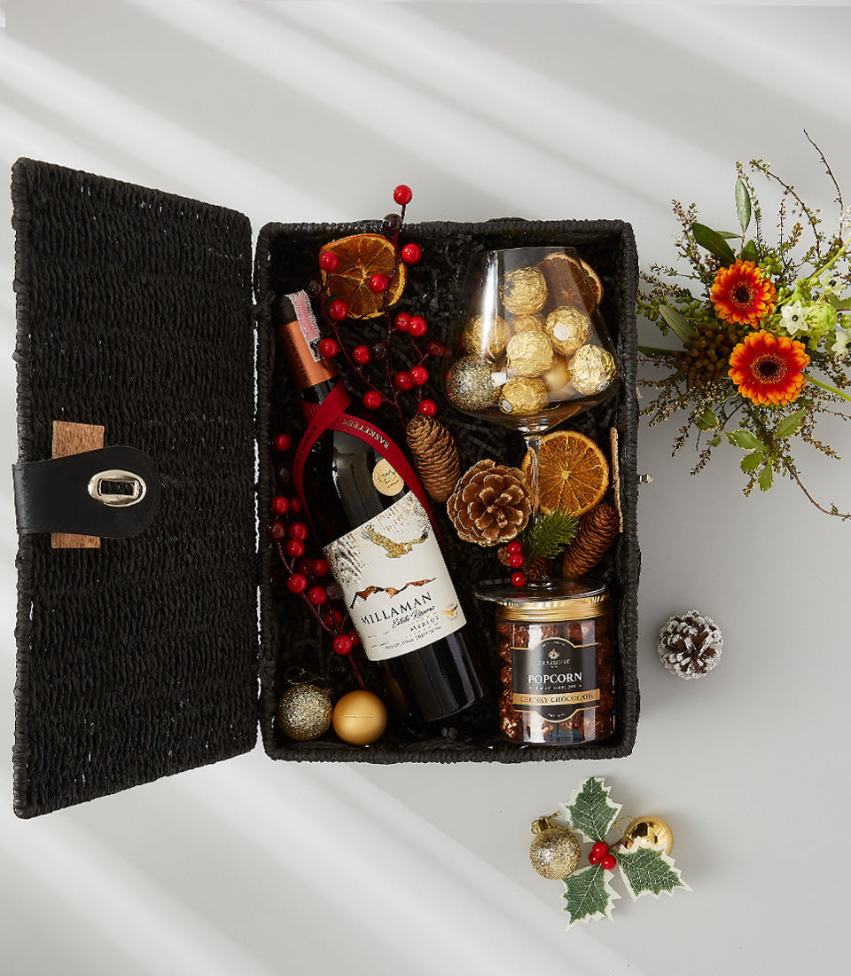 Premium red wine gift basket with gold-wrapped chocolates, festive berries, and holiday botanicals