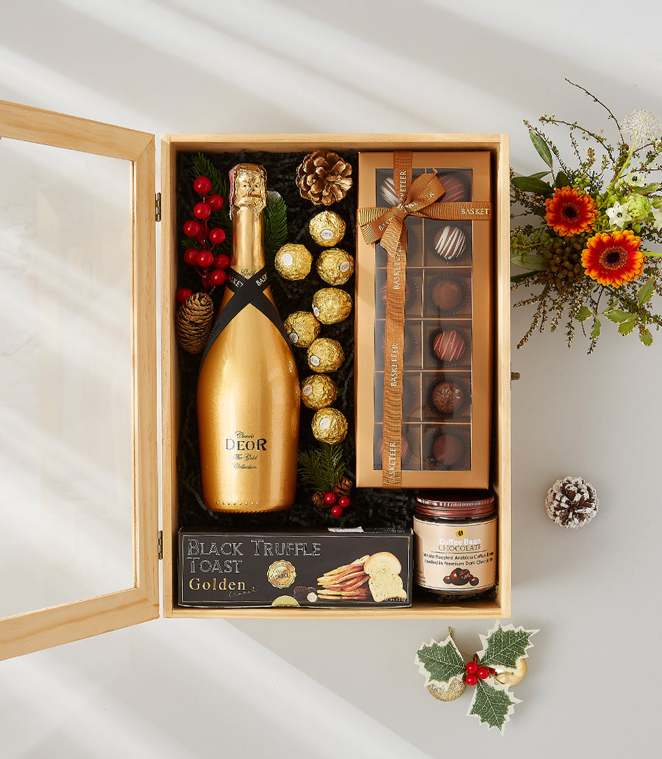 Luxury golden champagne gift box with artisan chocolates, gourmet crackers, and festive florals