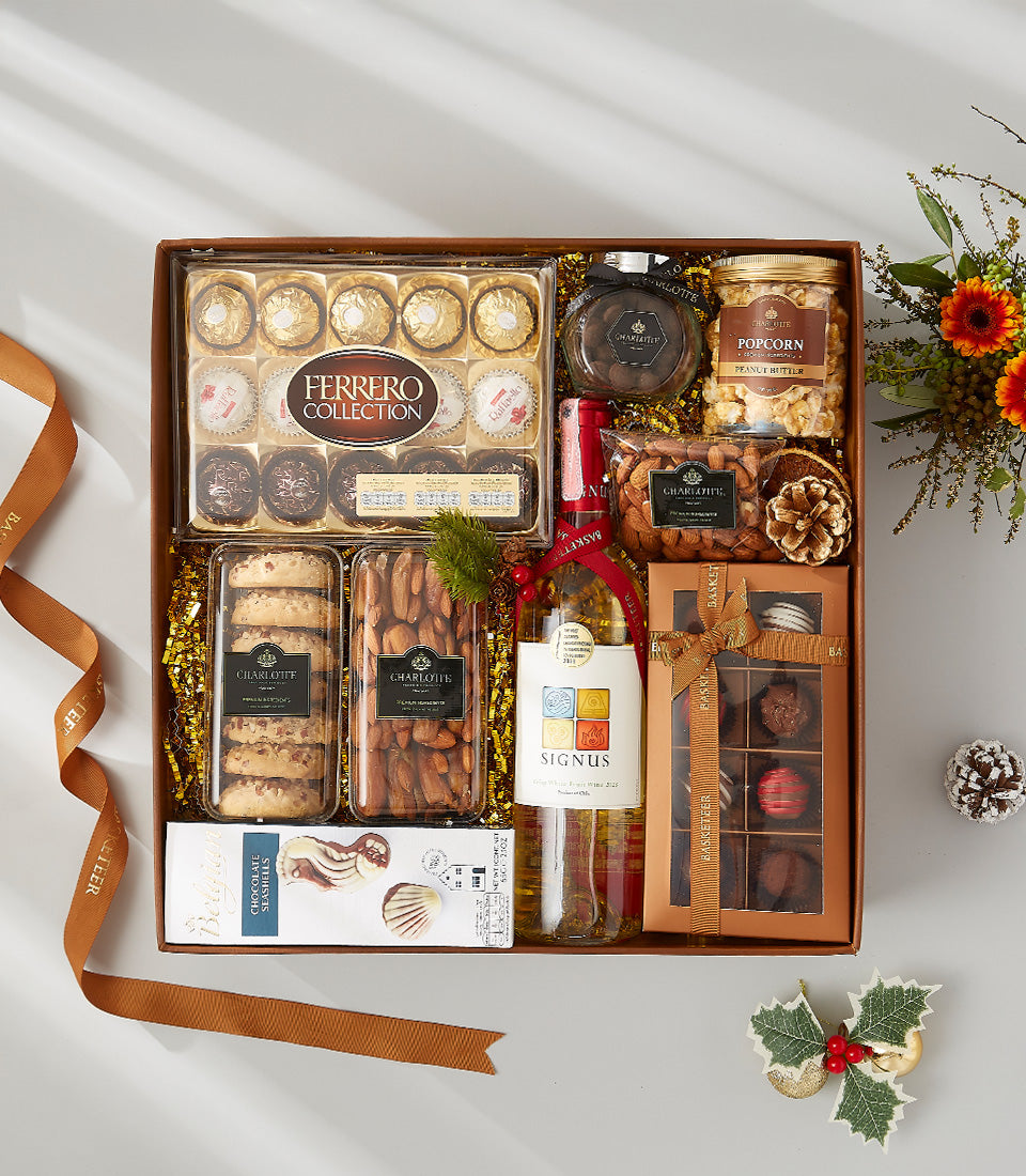 Luxury white wine gift box with gourmet chocolates, nuts, and artisan treats on gold shredded paper