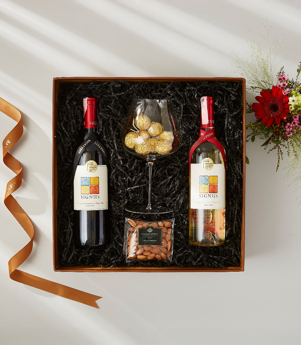 Luxury wine gift box with red and white SIGNUS bottles, Ferrero Rocher chocolates, almonds, and fresh red gerbera flowers