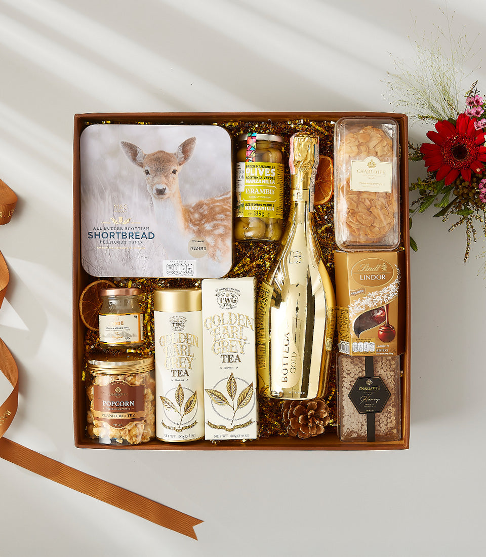 Premium wine gift box with gourmet snacks, shortbread, olives, tea, and chocolate in dark wood presentation