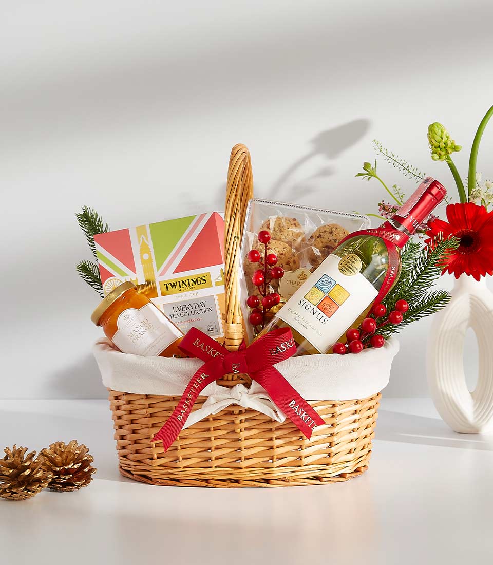 Luxury white wine gift basket with tea, preserves, and holiday florals in wicker with red ribbon
