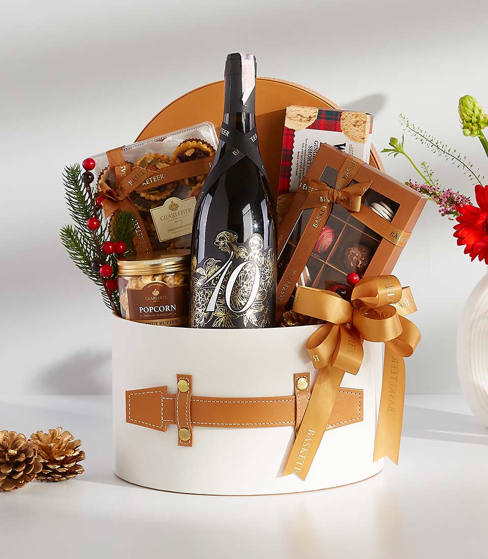 Luxurious festive gift basket with sparkling wine, gourmet chocolates, and holiday accents in white round container