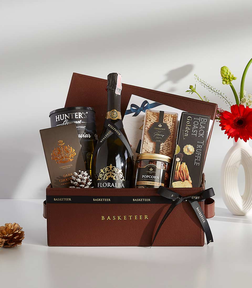 Luxury gift box with champagne, dark chocolate, gourmet caviar, and artisan treats in faux leather case