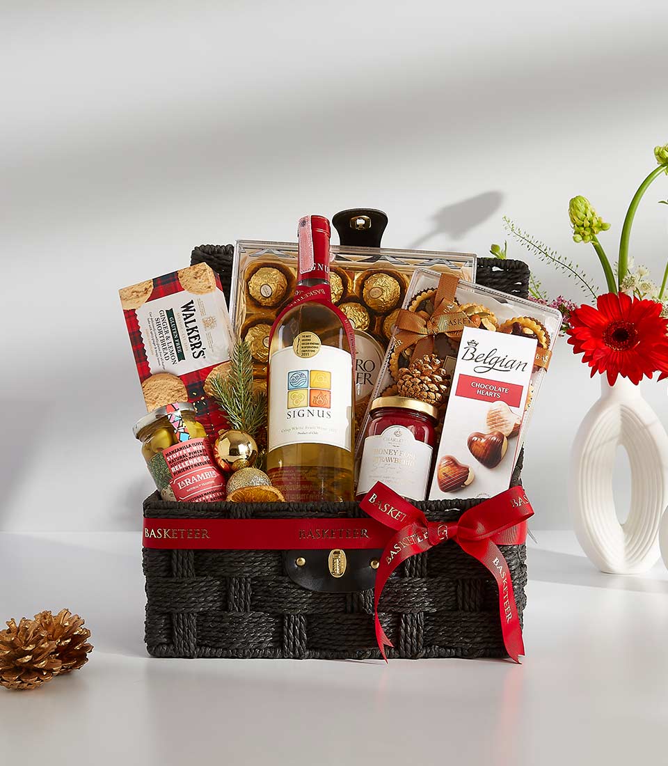 Luxury white wine gift basket with gourmet chocolates, shortbread, and festive holiday trimmings in dark woven basket