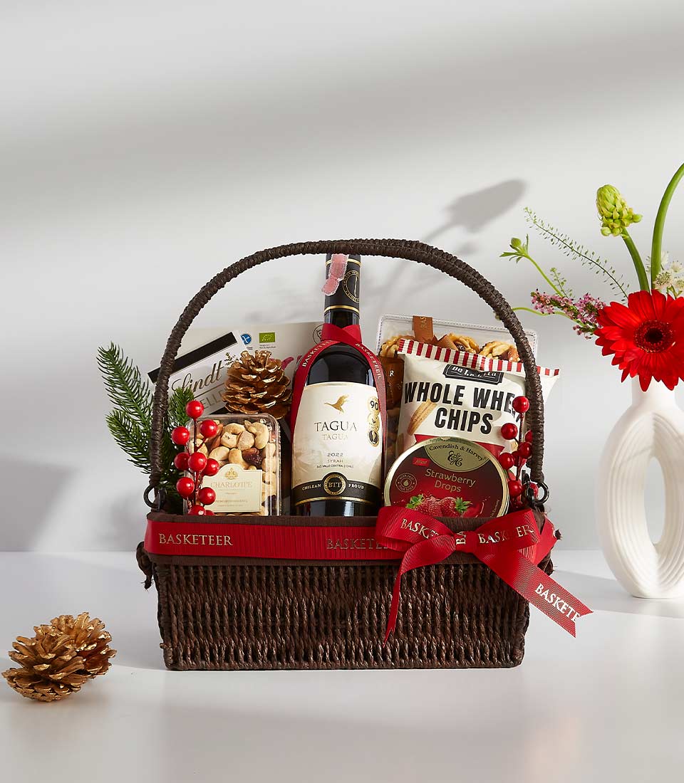 Premium red wine gift basket with gourmet treats, nuts, and Lindt chocolate in dark woven basket with red ribbon