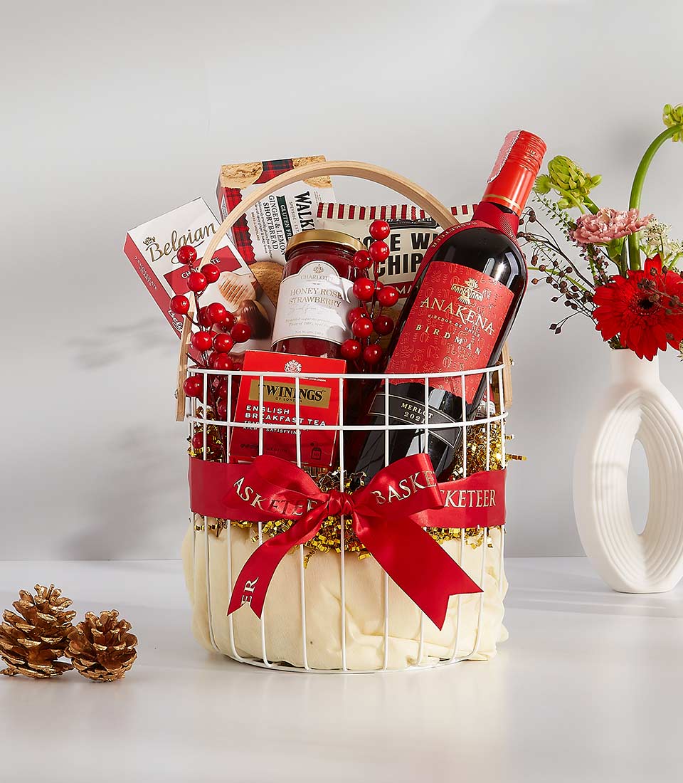 Luxurious holiday gift basket with red wine, gourmet treats, and festive red ribbon