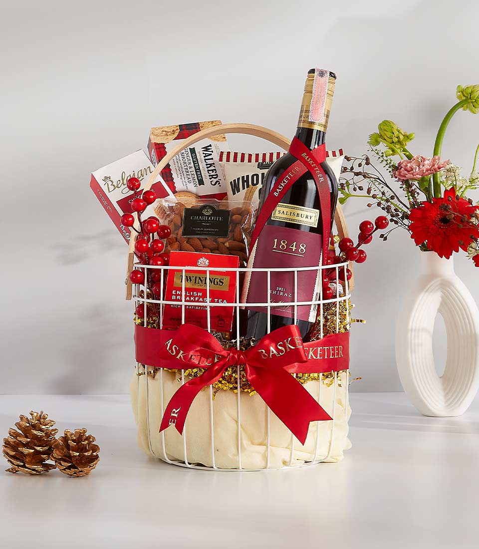 Luxe white wire gift basket with Shiraz wine, shortbread, Belgian chocolates, and gourmet treats tied with red satin bow