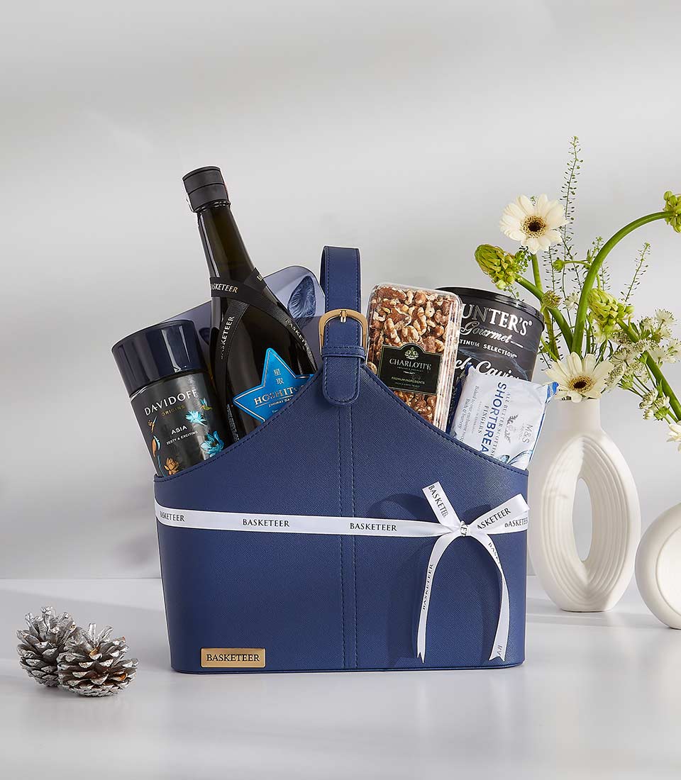 Luxury navy gift basket with red wine, gourmet treats, and white gerbera daisies arrangement