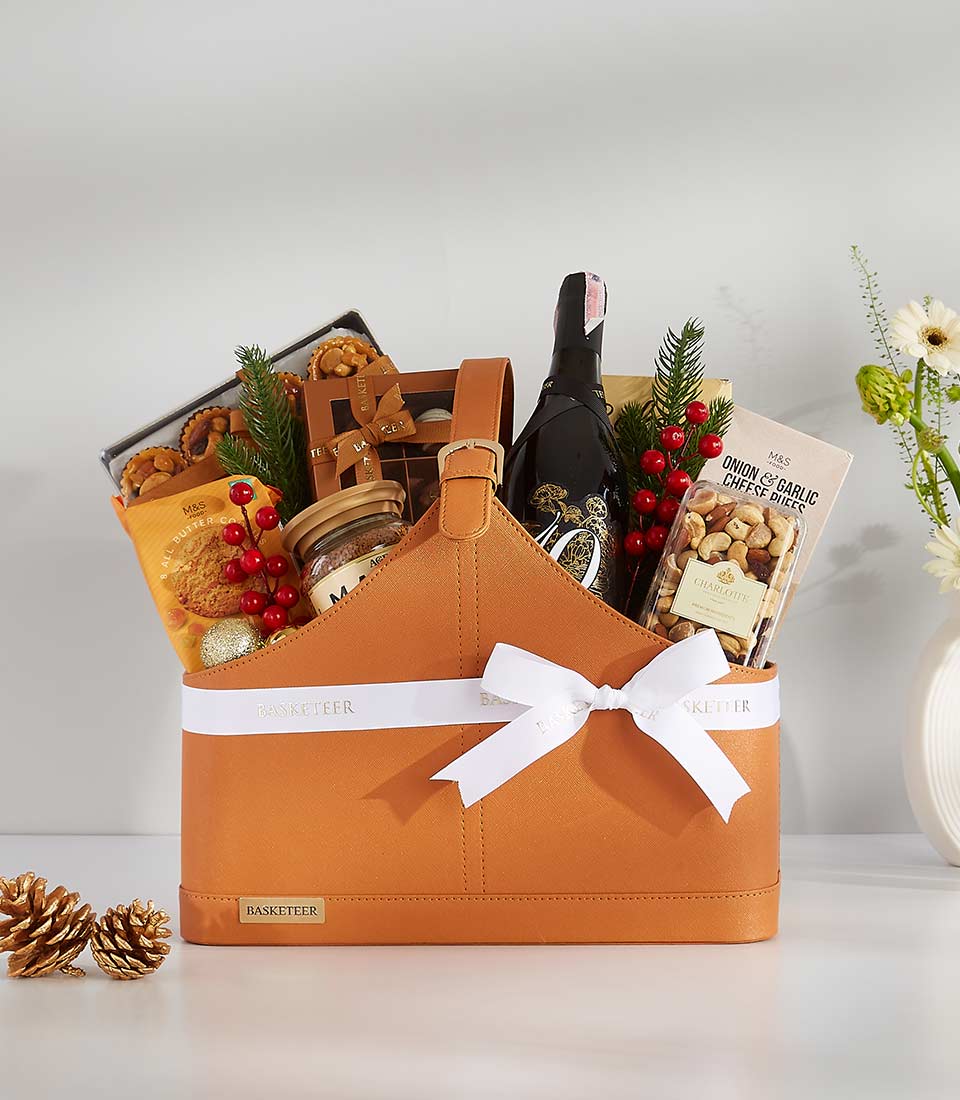 Premium wine gift basket with gourmet snacks, cookies, and holiday berry sprigs in faux leather presentation