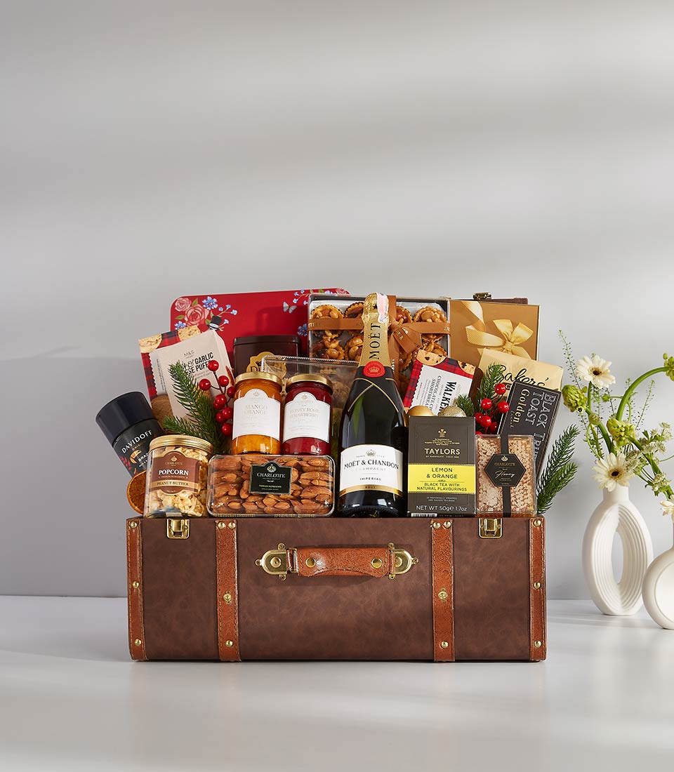 Luxury champagne and gourmet gift hamper in vintage leather trunk with preserves, tea, and treats